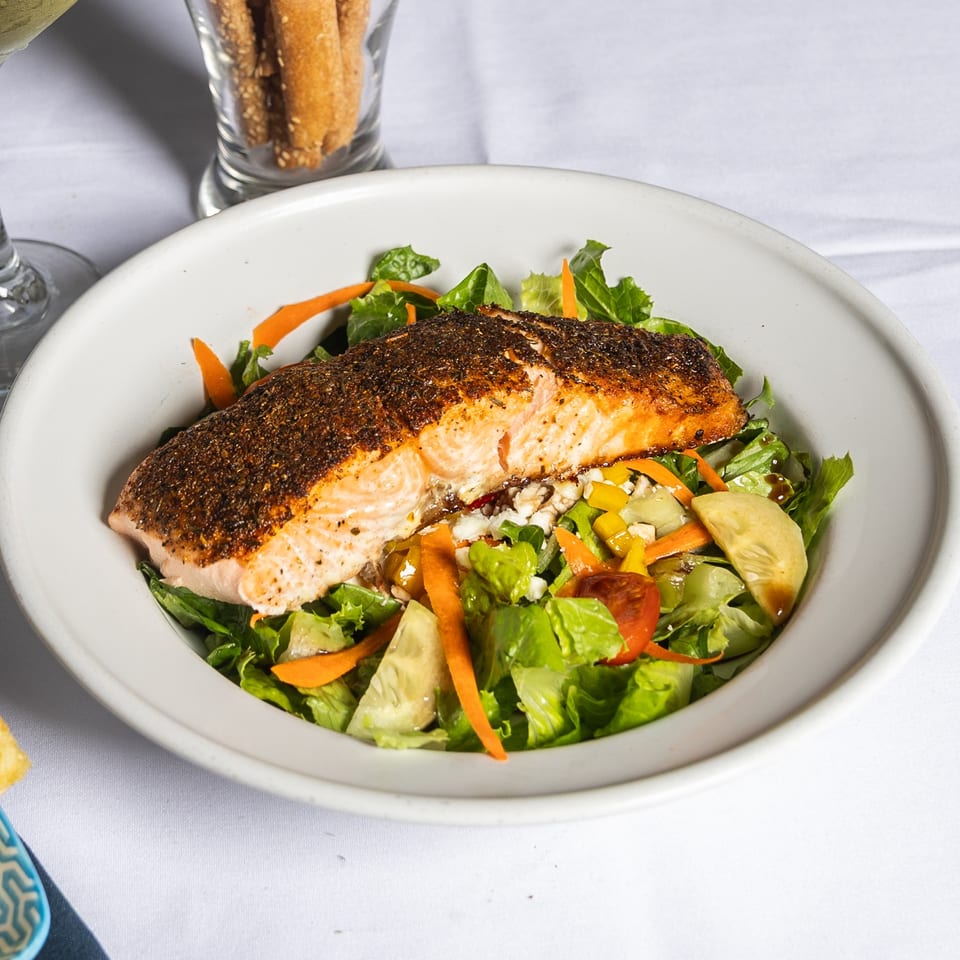 Seasoned salmon fillet on a fresh garden salad with feta, tomatoes, and carrots.